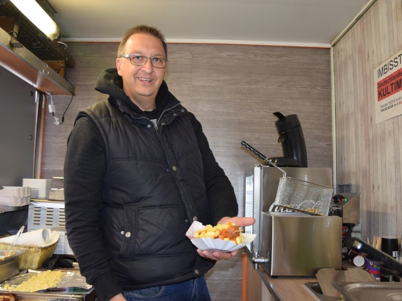 Marco Peters bietet Currywurst am Stiel.