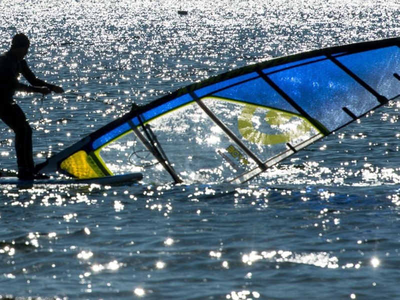 Ein Mann surft bei strahlendem Sonnenschein und sommerlichen Temperaturen auf dem Berzdorfer See bei Görlitz.