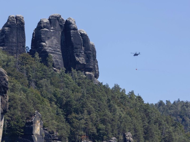Ein Löschhubschrauber der Bundeswehr ist bei den Waldbränden in der Sächsischen Schweiz im Einsatz. Die Situation im Waldbrandgebiet Nationalpark Sächsische Schweiz ist noch nicht unter Kontrolle. Der Waldbrand im Nationalpark hat den Aufschwung der Tourismuswirtschaft nach der Corona-Pandemie gestoppt.