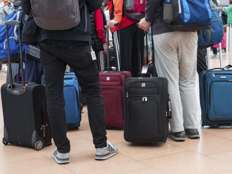 Reisende stehen mit ihrem Gepäck am Flughafen.