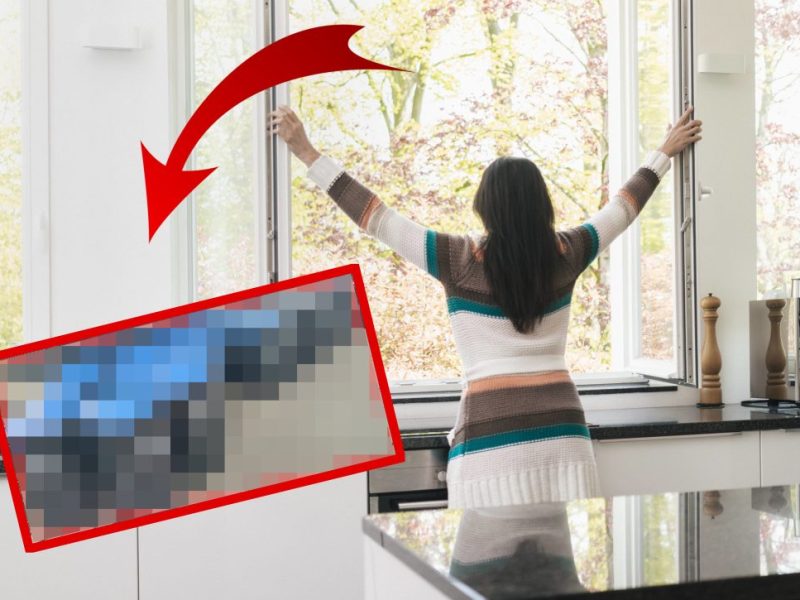 Frau reißt Küchenfenster auf