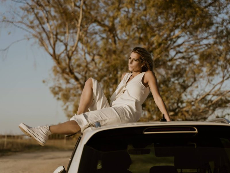 Urlaub mit Mietwagen Frau sitzt auf Auto