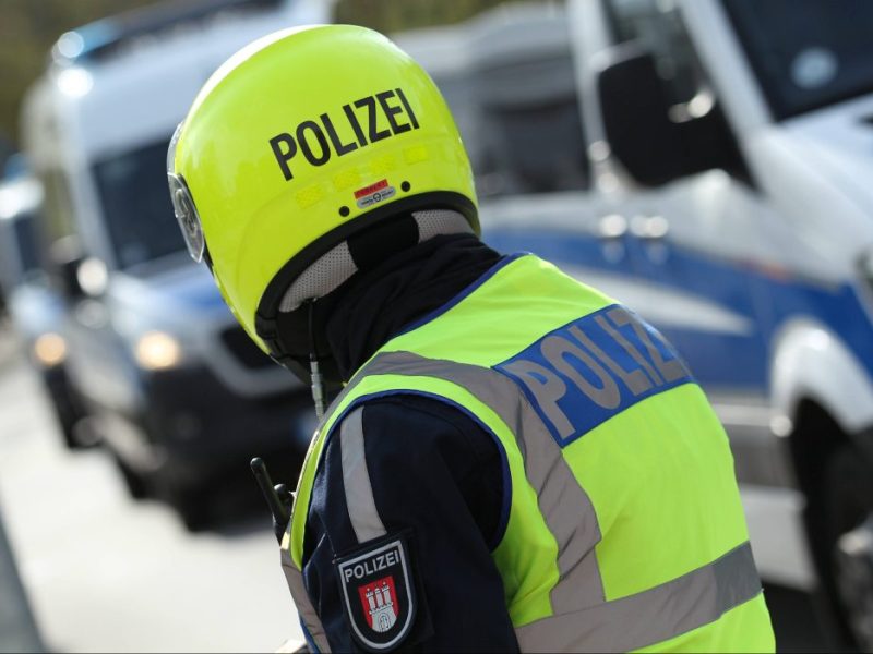 Polizist und Polizeiwagen im Hintergrund