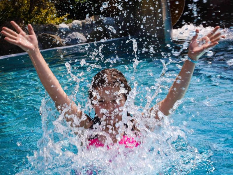 Mädchen spritz mit Wasser in Schwimmbecken