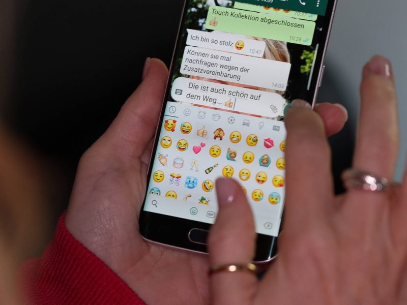 die Hände einer Frau tippen eine Nachricht in den Messenger Whatsapp auf einem Smartphone.