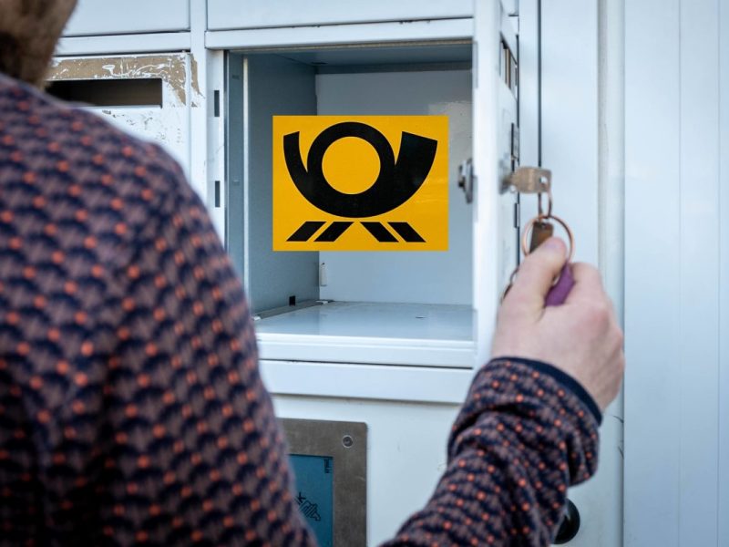 Mann öffnet leeren Briefkasten mit Deutsche Post-Logo drin