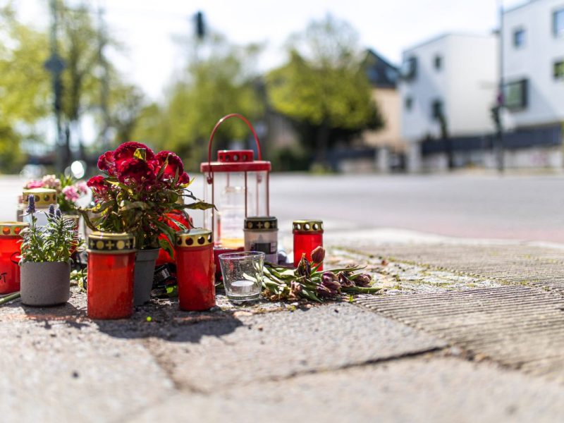 Trauerstelle an einer Straße mit Blumen und Kerzen