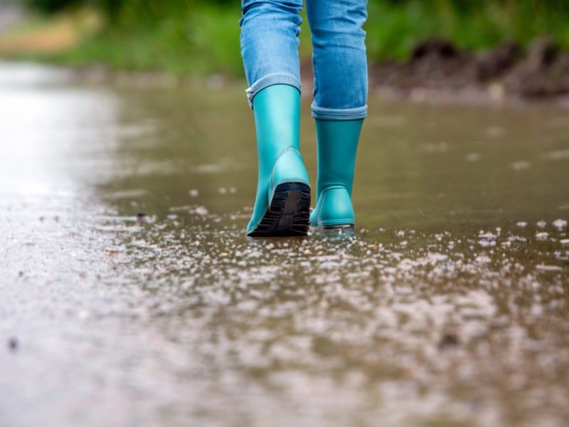 Frau läuft mit Gummistiefeln durch Regen
