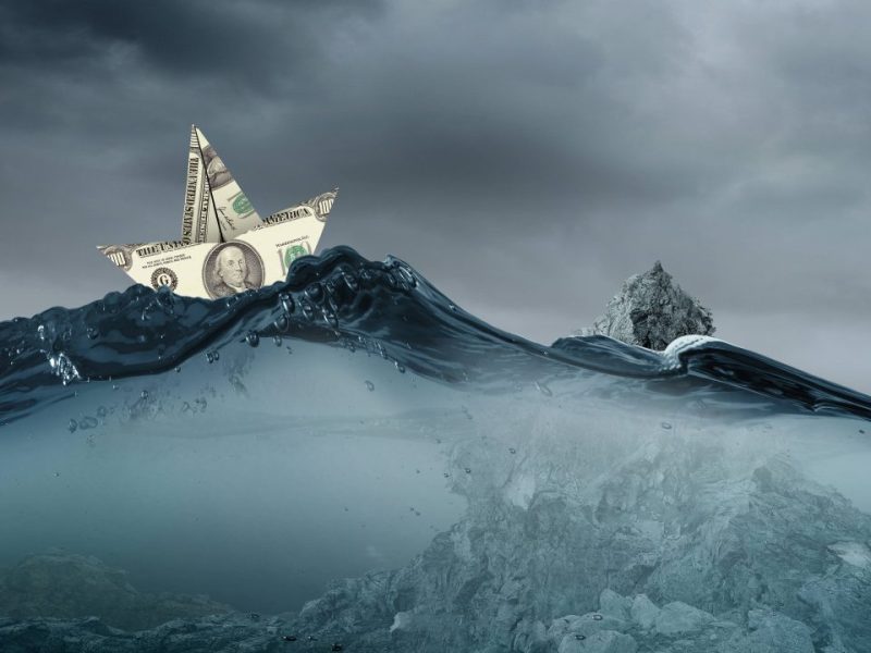 Illustration eines Bootes, welches durch einen Geldschein dargestellt wird wird. Das Boot treibt im stürmischen Meer.