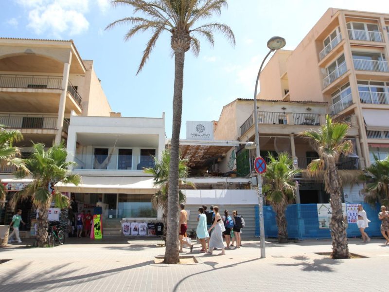 Menschen gehen an der Playa de Palma entlang. Im Hintergrund ist der Medusa Beach Club zu sehen.